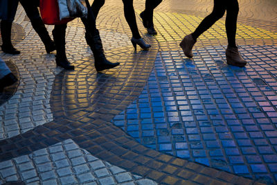 Low section of people walking on cobblestone