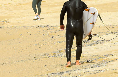 Low section of people walking on beach