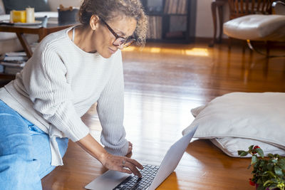 Side view of young man using laptop at home