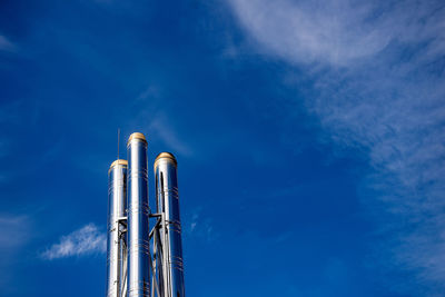 Low angle view of smoke stacks against blue sky