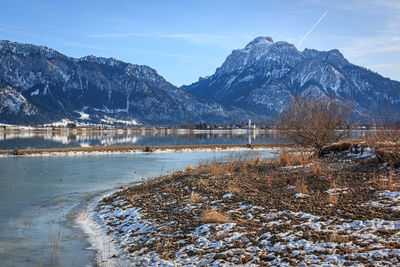 Scenic view of lake by snowcapped mountains against sky