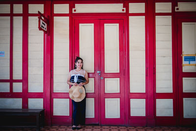 Woman standing against red wall