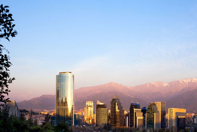 Modern cityscape and mountain against blue sky