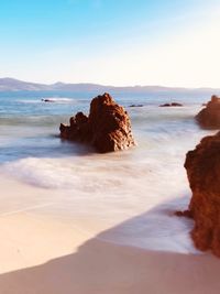 Rock formation on beach against sky