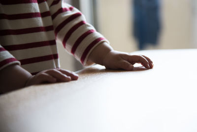 Midsection of kid standing by table at home