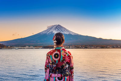 Rear view of woman against sky during sunset