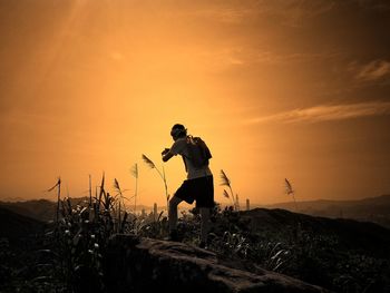 Man standing on land against sky during sunset
