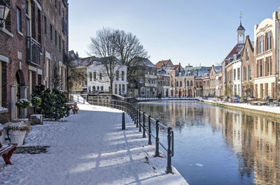 Canal amidst buildings in city during winter