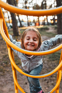 Playful happy girl preschooler playing on a playground climbing on monkey bars