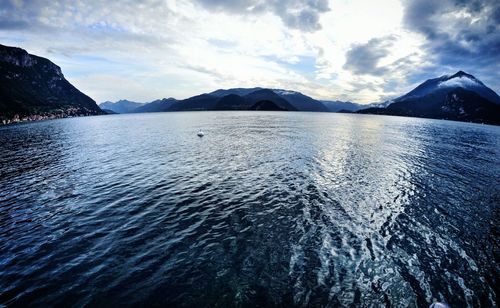 Scenic view of lake como by mountain range against cloudy sky