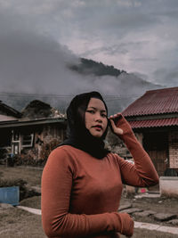 Portrait of young woman standing against sky