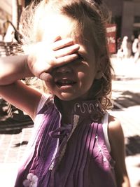 Close-up portrait of girl gesturing on footpath during sunny day