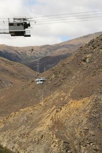 Overhead cable car on road against sky