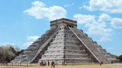 Tourists at historical building against cloudy sky