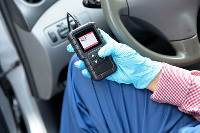 Close-up of hand holding mobile phone in car