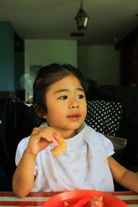 Cute girl eating food while sitting at home