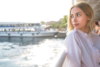 Thoughtful young woman on boat in sea against clear sky