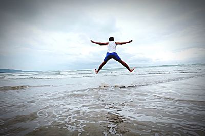 Full length of man jumping over sea against sky