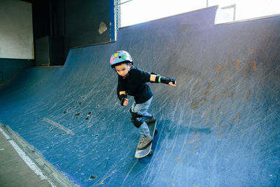 Young boy focused as he skates down a ramp