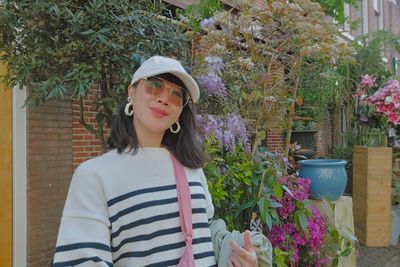 Portrait of young woman standing against plants