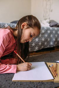 The girl after school plays at home, draws with pencils and felt-tip pens