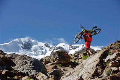 Man jumping in mountains against clear blue sky