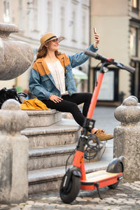 Full length of woman taking selfie while sitting outdoors