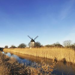 Traditional windmill on field against clear blue sky