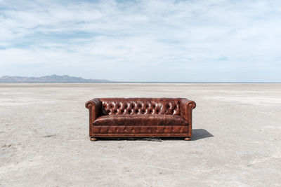 Sofa at salt flat against sky