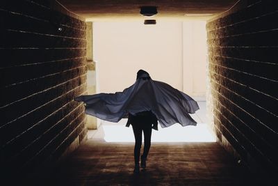 Rear view of woman walking in tunnel