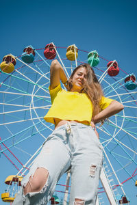 Low angle view of smiling young woman against sky