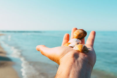 Midsection of person on sea shore against sky