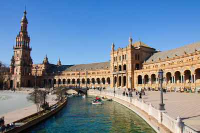 View of canal and buildings against clear blue sky