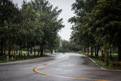 Road amidst trees against sky in city