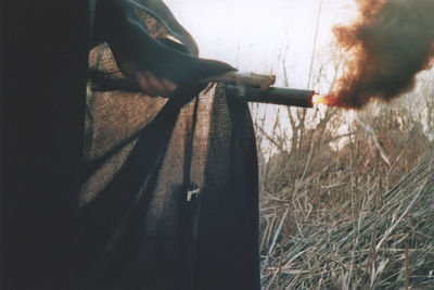 Close-up of man holding cigarette on field