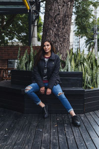 Portrait of smiling young woman sitting on bench