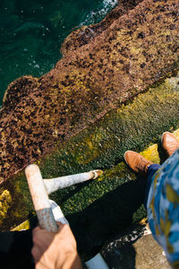 Low section of man standing on staircase at sea