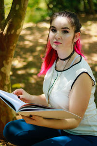 Portrait of young woman with file in park