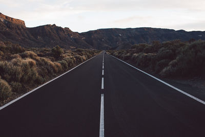 Road leading towards mountains against sky