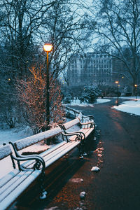 Snow-covered benches in the park and a burning lantern early in the morning