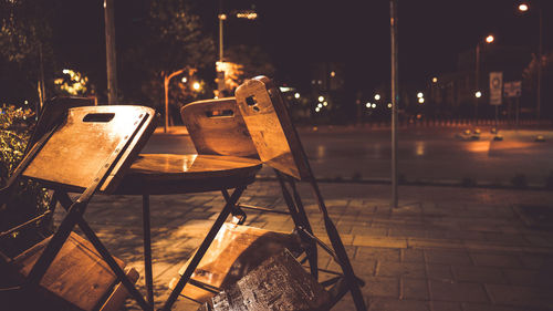 Empty chairs and tables in street at night