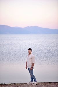 Full length portrait of man standing on a beach against sky