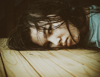 Close-up portrait of woman lying on table at home