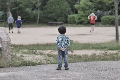 Rear view of boys walking on road