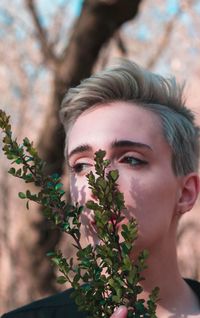 Close-up portrait of young woman with leaves outdoors