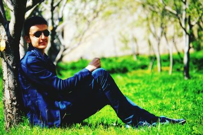 Man wearing sunglasses sitting on grassy field at public park