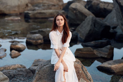 Portrait of young woman standing against rock