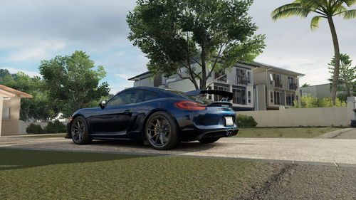 Car on street by trees and buildings against sky