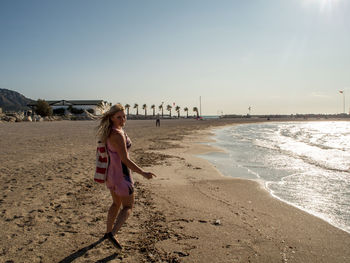 Woman standing at beach against sky