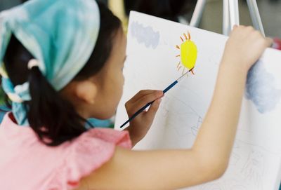 Close-up of girl painting on canvas outdoors